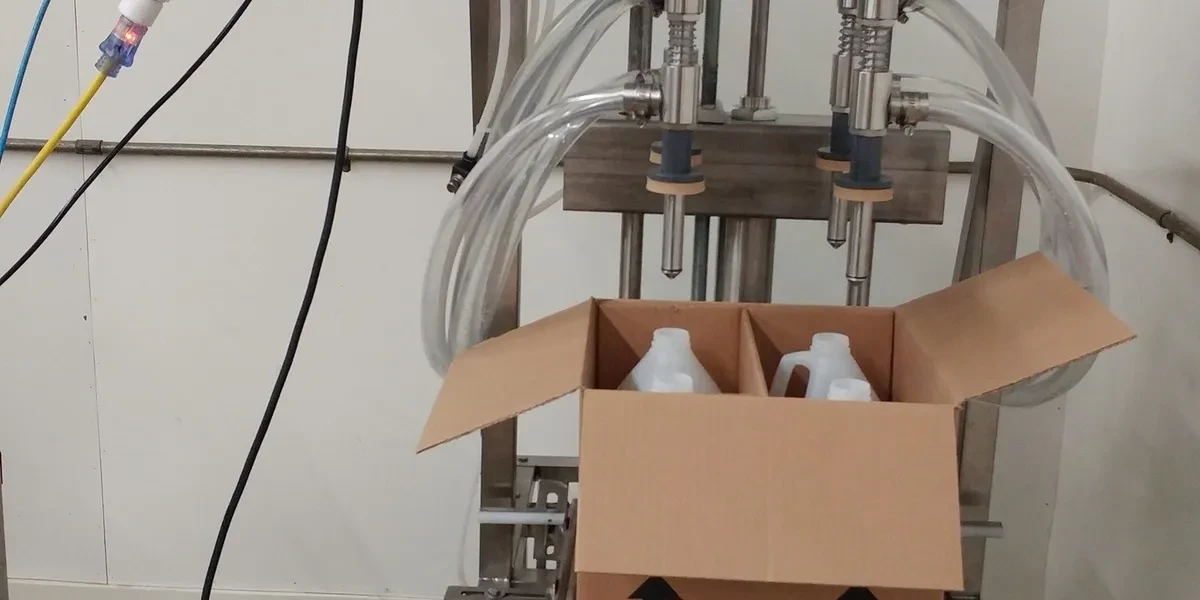 Four head overflow filling machine filling bottles in a box